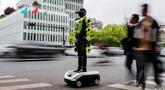 Orang-orang berjalan melewati robot polisi humanoid di Hangzhou, provinsi Zhejiang Timur, Tiongkok pada Minggu 3 Mei 2026. 15 robot humanoid dikerahkan di Hangzhou, Provinsi Zhejiang, Tiongkok. (Agatha CANTRILL/AFP)