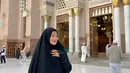 Gamis panjang berwarna hitam dipadukan dengan khimar warna senada jadi salah satu pilihan outfit simpel untuk umrah. [@titi_kamall]