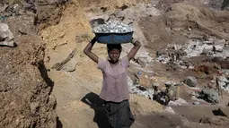 Bocah perempuan mengangkat bongkahan batu saat bekerja di sebuah tambang di Ouagadougou, Burkina Faso, 21 Desember 2015. Ini untuk menyelamatkan masa depan 168 juta anak yang sudah bekerja di usia dini. (NABILA EL Hadad / AFP)