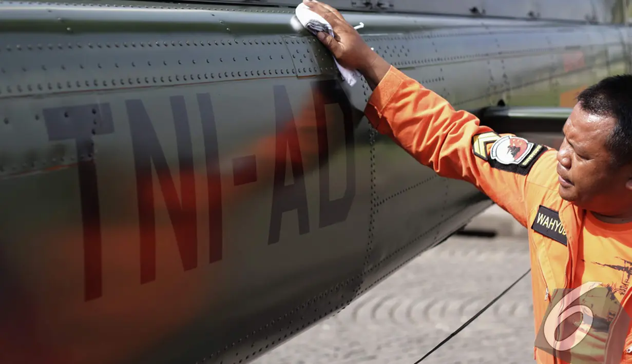 Seorang anggota TNI membersihkan bagian belakang helikopter yang akan dipamerkan pada Pameran Alutsista TNI AD di Hari Juang Kartika TNI AD Ke-69, Jakarta, Rabu, (10/12/2014). (Liputan6.com/Faizal Fanani)