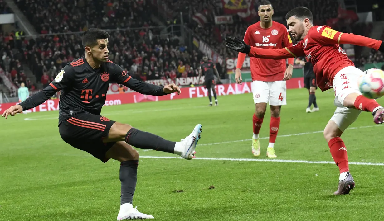 <p>Bek Bayern Muenchen, Joao Cancelo berusaha mengumpan bola dari kawalan bek Mainz 05, Aaron Martin selama pertandingan babak 16 besar Piala Jerman (DFB Pokal) di Mewa Arena, Mainz, Jerman (1/2/2023). Di debutnya, Joao Cancelo membantu Bayern mengamankan tiket perempat final ajang DFB Pokal dengan mengalahkan Mainz 4-0. (AFP/Thomas Kienzle)</p>
