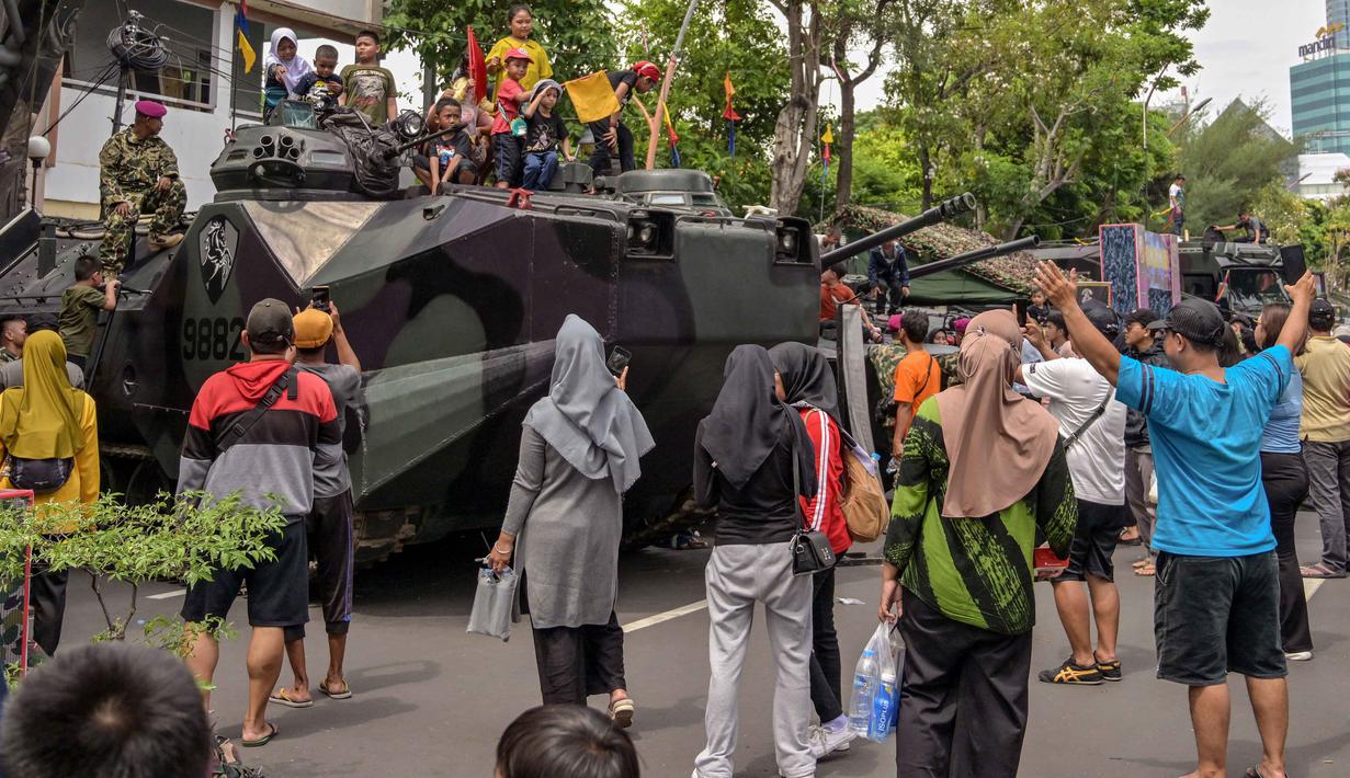 Menandai peringatan Hari Ulang Tahun ke-80, Korps Marinir TNI AL menggelar pameran alat utama sistem senjata atau alat utama sistem pertahanan (Alutsista) serta sejumlah kegiatan lainnya di sekitaran Gedung Negara Grahadi, Surabaya, Jawa Timur. Tampak dalam foto, warga berfoto bersama kendaraan militer selama Pameran Marinir Indonesia, yang menandai peringatan Hari Ulang Tahun ke-80 Korps Marinir TNI AL di Surabaya, Jawa Timur pada Minggu 9 November 2025. (JUNI KRISWANTO/AFP)