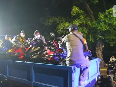 Petugas mengangkut sejumlah motor yang berhasil diamankan dalam patroli penegakan protokol kesehatan COVID-19 di Jalan Veteran, Jakarta Pusat, Sabtu (26/12/2020). Operasi gabungan itu dilakukan menyusul meningkatnya penyebaran COVID-19 di Ibu kota. (Liputan6.com/Herman Zakharia)