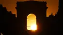 Foto yang diambil pada 2 Agustus 2022 menunjukkan Arc de Triomphe saat matahari terbenam, di Paris. Peristiwa yang dikenal sebagai "Paris Henge" ini di mana matahari sejajar dengan Champs Elysées, Arc de Triomphe dan Arche de la Défense. (Photo by Stefano RELLANDINI / AFP)