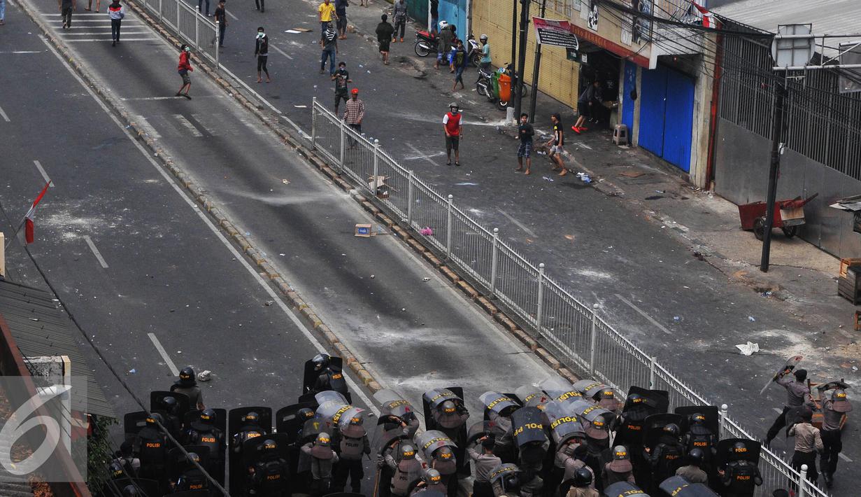 Petugas gabungan berusaha menahan serangan warga Kampung Pulo yang menolak pengusuran, Jakarta, Kamis (20/8/2015). Penggusuran pemukiman Kampung Pulo dilakukan oleh 2.200 personel gabungan untuk normalisasi Sungai Ciliwung. (Liputan6.com/Herman Zakharia)