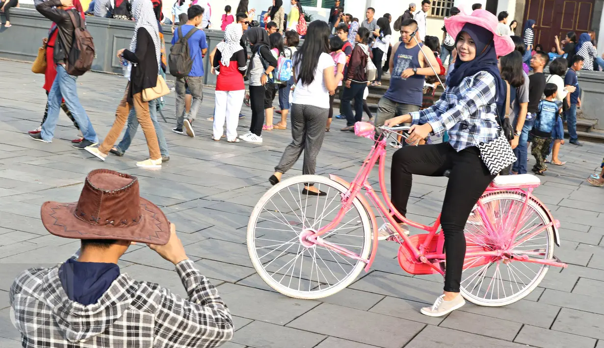 Seorang remaja berpose diatas sepeda kuno di Kota Tua, Jakarta, Minggu (8/5).Dengan latar bangunan tua di kawasan tersebut menjadikan banyak remaja yang mengabadikan gambar mereka. (Liputan6.com/Imma nuel Antonius)