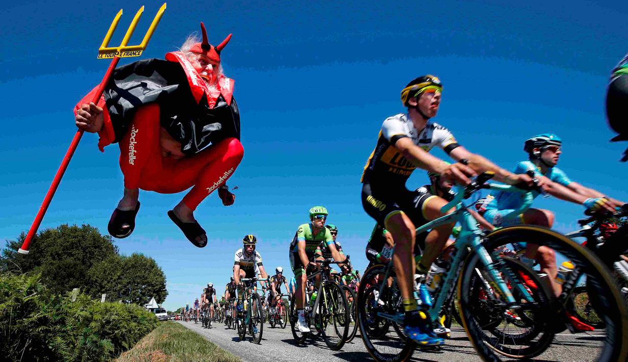 Pebalap sedang melewati Didi Senft, seorang penggemar balap sepeda yang dikenal dengan nama 'El Diablo' (The Devil) di Etape 7 Tour de France yang berjarak 190.5-km dari Livarot ke Fougeres, Prancis, (10/7/2015). (REUTERS/Eric Gaillard)