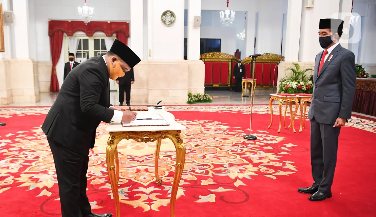 Kepala Badan Pelindungan Pekerja Migran Indonesia (BP2MI) Benny Rhamdani menandatangani dokumen disaksikan Presiden Joko Widodo  usai pelantikan di Istana Negara, Jakarta, Rabu (15/4/2020). (Antarafoto/Hafidz Mubarak/Pool)