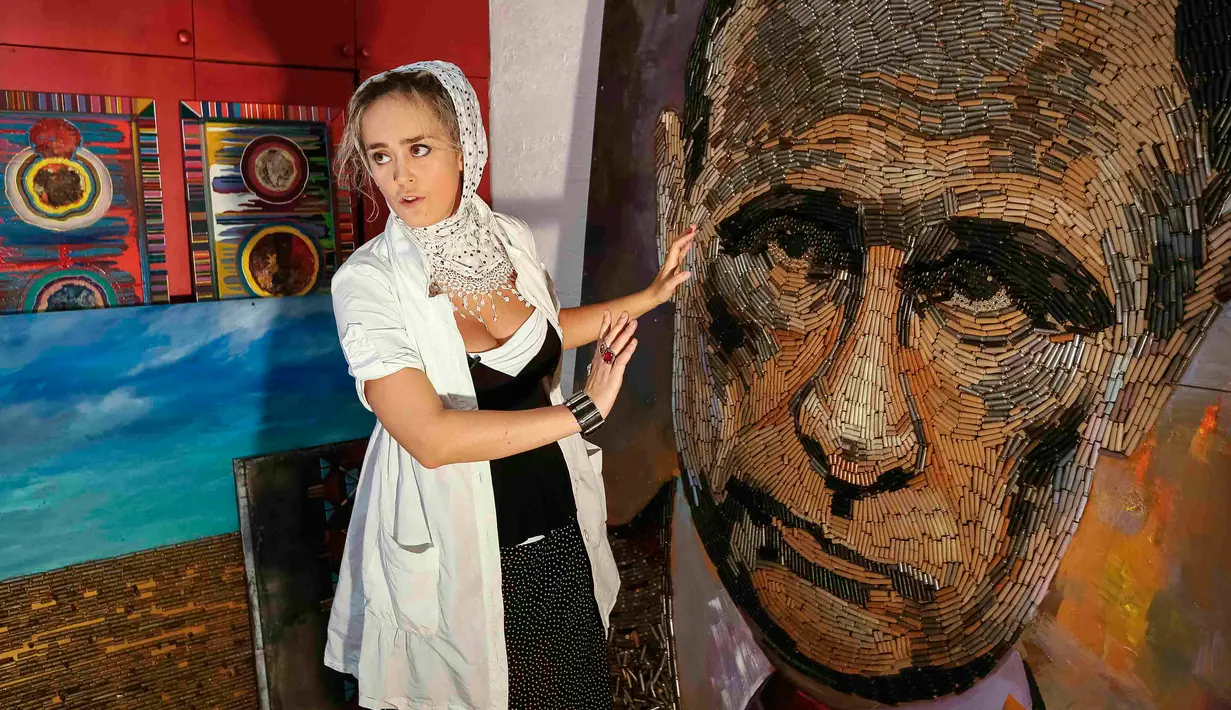 Seniman asal Ukraina, Dariya Marchenko memperlihatkan lukisan wajah Presiden Rusia, Vladimir Putin yang dibuatnya di Kiev, Ukraina (27/7/2015). 5.000 peluru dihabiskan Dariya yang diambil dari lokasi peperangan di Ukraina Timur. (REUTERS/Gleb Garanich)