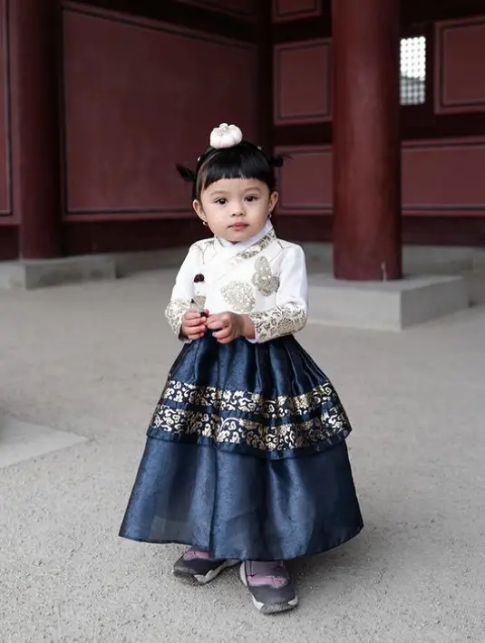 Ameena tampil menggemaskan mengenakan hanbok waena putih dan navy. Lengkap dengan hiasan rambutnya. [@attahalilintar]