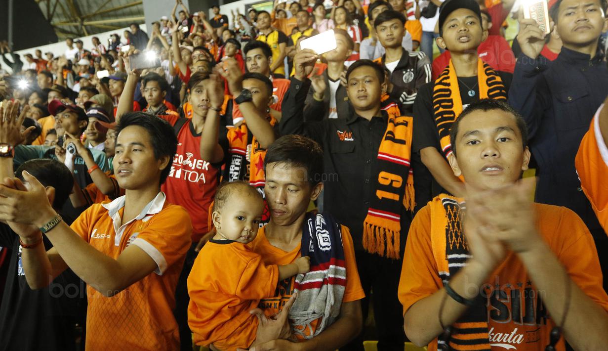 Seorang The Jakmania membawa anakanya saat menyaksikan laga terakhir Persija di Liga 1 di Stadion Patriot, Bekasi, Minggu (12/11/2017). Persija menang 2-1 atas Bhayangkara FC. (Bola.com/ M Iqbal Ichsan)