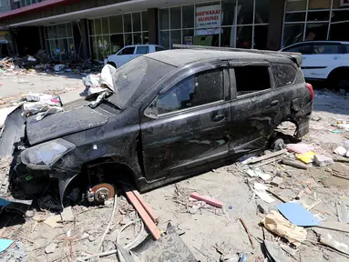 Sebuah mobil Datsun menjadi incaran jarahan korban gempa dan tsunami di Palu Grand Mal, Palu, Jumat (5/10). Warga korban gempa bumi mengambil ban dan interior mobil. (Liputan6.com/Fery Pradolo)