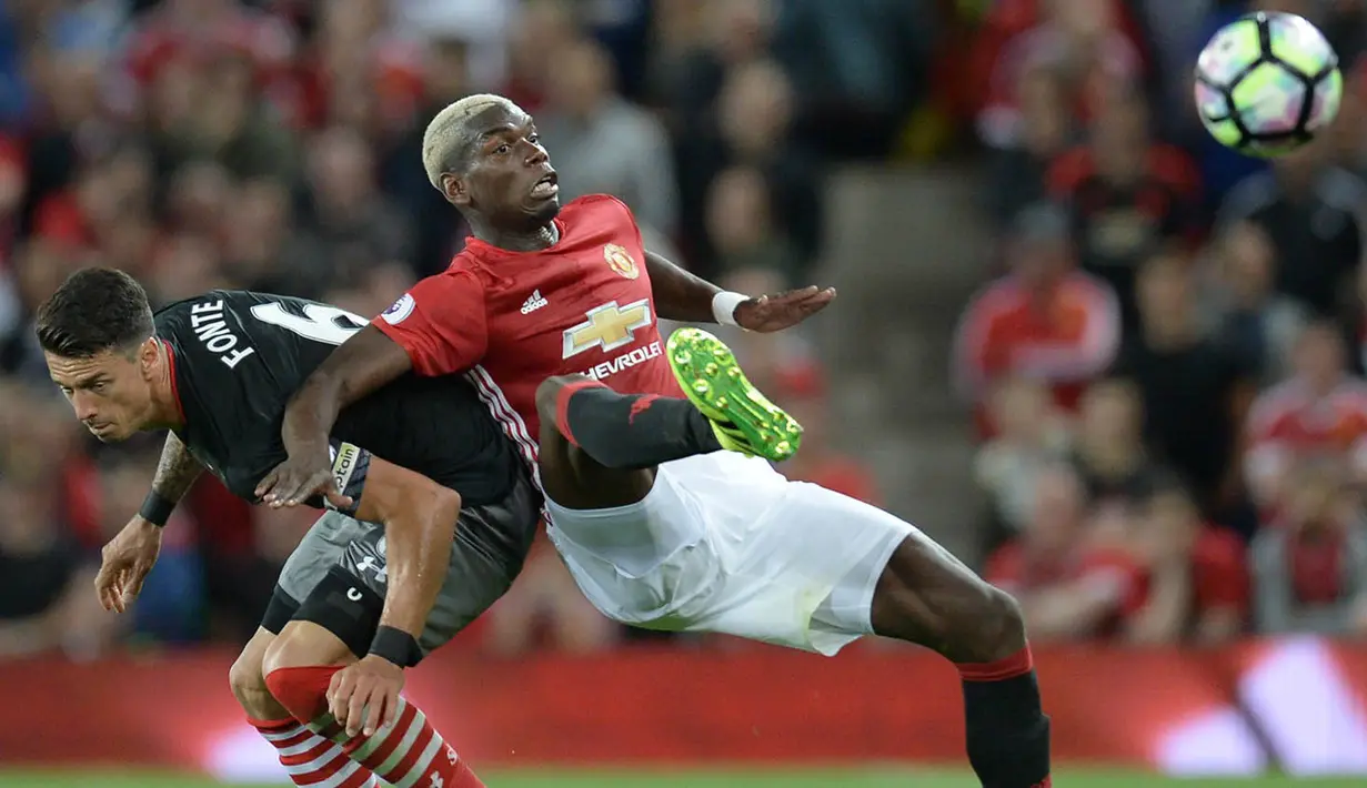 Gelandang Manchester United. Paul Pogba, berebut bola dengan bek Southampton, Jose Fonte. Pertandingan ini merupakan laga perdana Paul Pogba setelah kembali berseragam Setan Merah. (AFP/Oli Scarff)