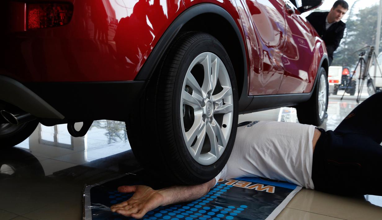 Aksi Norik Yajian ketika dilindas mobil dibagian lengannya pada sebuah atraksi di Tbilisi, Georgia, Selasa (16/2). Aksi nekat tersebut dilakukan untuk memecahkan rekor Guinness. (REUTERS/David Mdzinarishvili)
