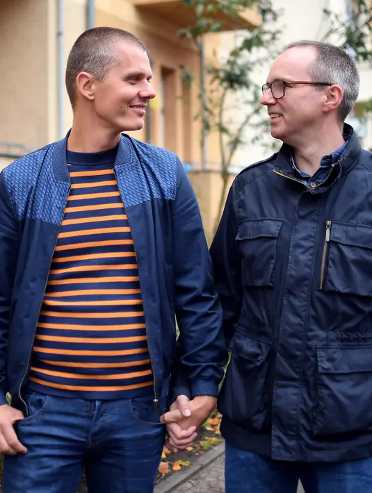 Pasangan Gay Michael (kiri) dan Kai Korok berpegangan tangan di Berlin, (10/10). Pasangan ini menyerahkan sertifikat pernikahan mereka untuk meminta adopsi legal seorang anak laki-laki berusia dua tahun. (AFP Photo/dpa/Britta Pedersen/Jerman Out)