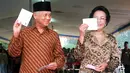 Presiden BJ Habibie didampingi istrinya Ainun Habibie menunjukkan surat suara sebelum melakukan pencoblosan dalam pemilu di Jakarta, 7 Juni 1999. Makam Habibie bakal bersebelahan dengan sang istri tercinta, Ainun Habibie. (AFP Photo/Agus Lolong)