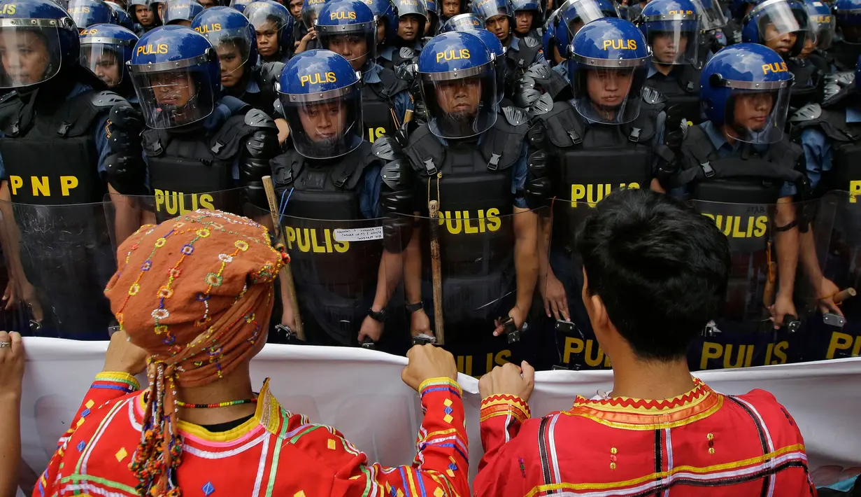 Barisan polisi anti huru-hara berjaga mengamankan aksi massa di dekat Kedutaan Besar AS di Manila, Filipina (11/11). (AP Photo/Aaron Favila)