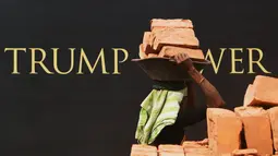 Seorang buruh wanita India mengangkat batu bata untuk pembangunan konstruksi Trump Tower atau Menara Trump di Kolkata, India (20/2). Trump Jr juga menjadi tuan rumah makan malam di Kolkata untuk menjamu para investor properti. (AFP/ Dibyangshu Sarkar)