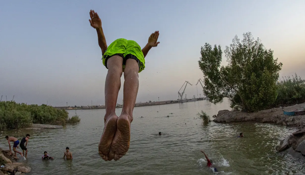 Seorang pemuda terjun ke Sungai Shatt Al-Arab di Kota Basra, Irak, Selasa (9/6/2020). Sungai yang memiliki panjang sekitar 200 Km ini menandai perbatasan antara Irak dan Iran. (Hussein FALEH/AFP)