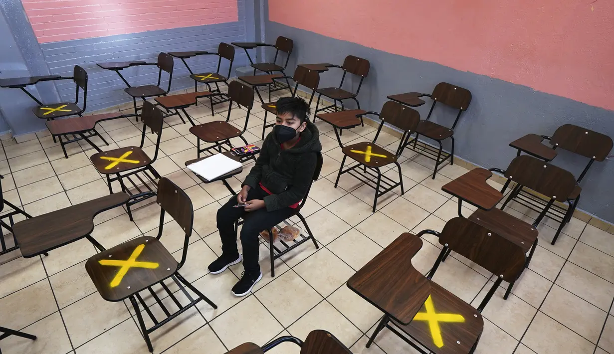 Seorang siswa duduk sendirian dalam kelas saat sekolah tatap muka di sekolah menengah Republic of Argentina di Iztacalco, Mexico City, Meksiko, Senin (30/8/2021). Jutaan anak Meksiko mulai menjalani sekolah tatap muka. (AP Photo/Marco Ugarte)