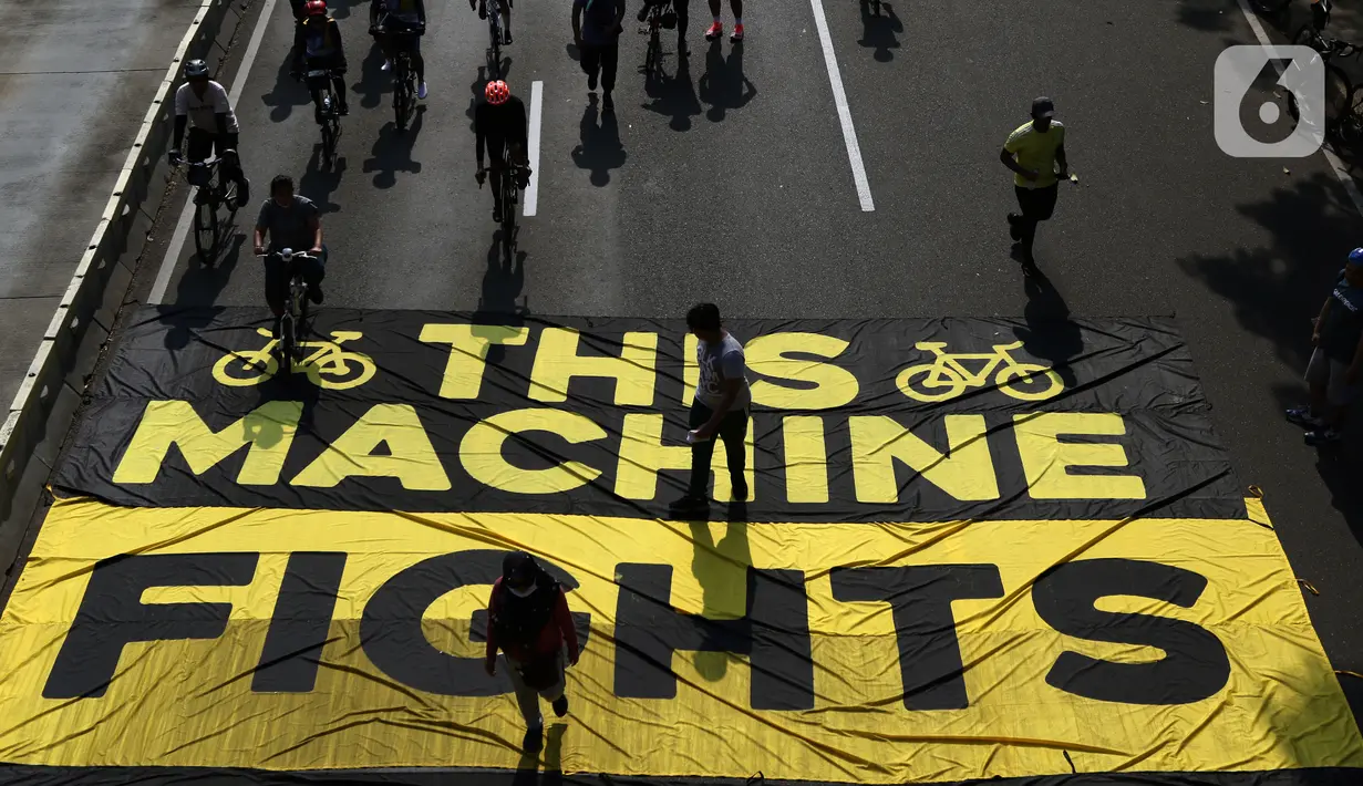 Pesepeda melintas di atas banner yang dibentangkan aktivis Greenpeace dan Bike2Work di Jalan Jenderal Sudirman, Jakarta, Minggu (5/6/2022). Aksi untuk mengkampanyekan penggunaan sepeda sebagai kendaraan ramah lingkungan dan solusi pembangunan Jakarta Kota Ramah Pesepeda. (Liputan6.com/Helmi Fithriansyah)