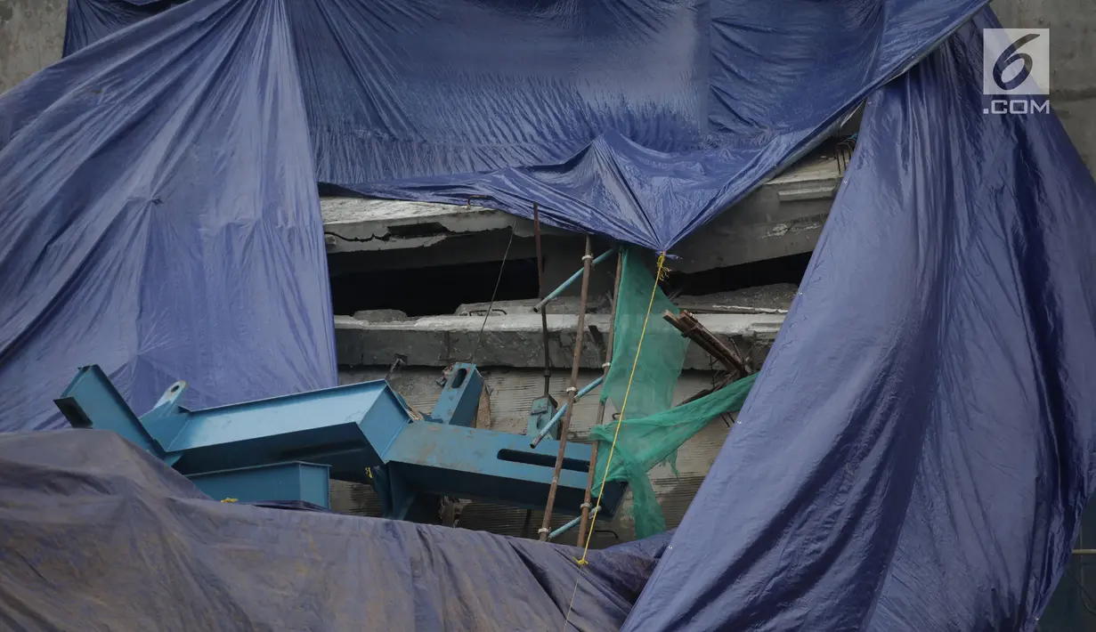 Terpal menutupi box girder beton proyek light rapid transit (LRT) yang roboh di Kayu Putih, Jakarta Timur, Senin (22/1). Dari data yang dihimpun diketahui kecelakaan terjadi sekitar pukul 00.30 WIB di antara pilar 28 dan 29. (Liputan6.com/Arya Manggala)