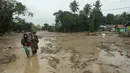 Penduduk desa berjalan melalui daerah banjir di desa Radda di Kabupaten Luwu Utara, Sulawesi Selatan (14/7/2020). Akibat musibah banjir bandang ini setidaknya sekitar 15 orang tewas dan belasan lainnya dinyatakan hilang. (AFP/Aryanto)