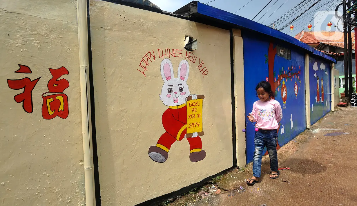 Anak kecil berjalan di dekat mural kelinci di Kampung Haji Bona, Depok, Jawa Barat, Kamis (19/1/2023). Perayaan tahun baru Imlek dimulai pada hari pertama penanggalan Tionghoa yaitu tanggal 22 Januari 2023 dan berakhir pada Cap Go Meh. (merdeka.com/Arie Basuki)