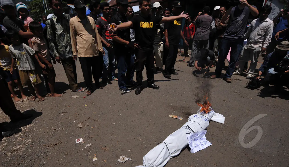 Pegiat Granat membakar pocong sebagai simbol hukuman mati bagi penjahat narkoba saat menggelar aksi  demonstrasi di depan pintu masuk Dermaga Wijaya Pura, Cilacap, Jateng, Jumat (6/3). (Liputan6.com/Johan Tallo)