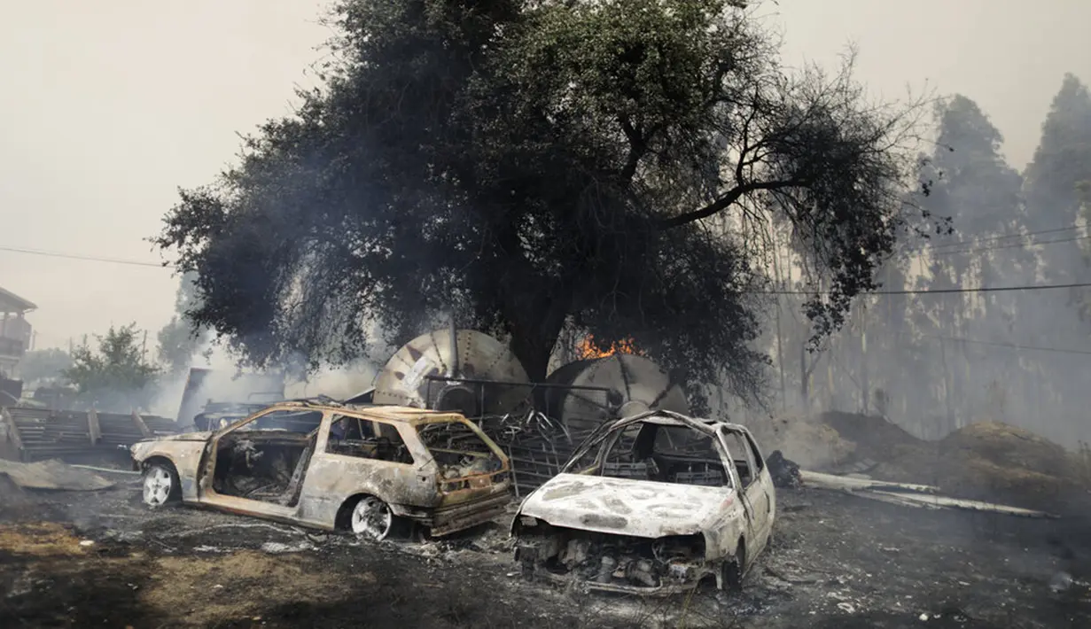 Asap mengepul dari tanah tempat kebakaran hutan mencapai dekat rumah yang membakar beberapa mobil di Desa Figueiras, di luar Leiria, Portugal, 12 Juli 2022. Ratusan petugas pemadam kebakaran di Portugal terus memadamkan api di pusat negara yang memaksa evakuasi puluhan orang dari rumah mereka sebagian besar di desa-desa sekitar Santarem, Leiria, dan Pombal. (AP Photo/Joao Henriques)