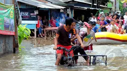 Hujan yang turun sejak Minggu (8/2) lalu, mengakibatkan kawasan perumahan mewah Garaharaya di Tangerang, Banten terendam air setinggi lebih kurang 90 cm. Tampak sejumlah bocah dievakuasi, Selasa (10/2/2015). (Liputan6.com/Faisal R Syam)