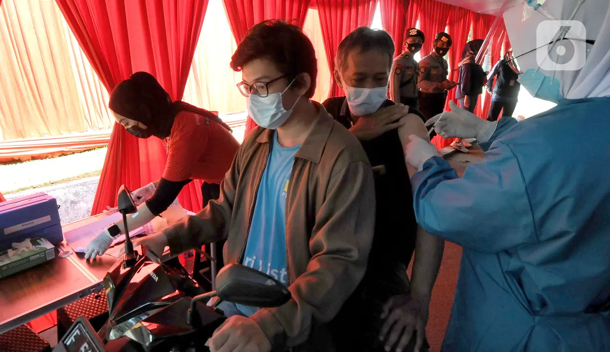 Paramedis menyuntikkan vaksin COVID-19 secara drive thru kepada penumpang sepeda motor di GOR Pajajaran, Kota Bogor, Jawa Barat, Rabu (17/3/2021). Kegiatan ini diselenggarakan oleh Halodoc, Gojek, dan Pemkot Bogor. (merdeka.com/Arie Basuki)