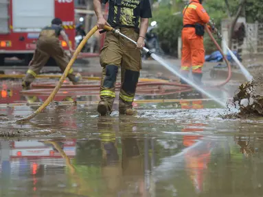 Petugas pemadam kebakaran menyemprotkan air untuk membersihkan lumpur sisa banjir di Kawasan Bukit Duri, Jakarta, Sabtu (4/1/2020). Meski banjir sudah mulai surut, jalan-jalan dan permukiman warga masih tertutup lumpur tebal. (merdeka.com/Imam Buhori)