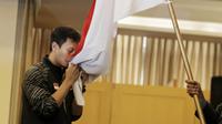 Atlet Bulutangkis Indonesia, Mohammad Ahsan, mencium bendera saat acara pelepasan di Hotel Atlet Century, Senayan, Selasa (8/5/2018). Acara pelepasan tersebut sekaligus merayakan ulang tahun PBSI ke 67. (Bola.com/M Iqbal Ichsan)