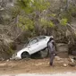 Sebuah mobil yang sebagian tergantung di pohon setelah terbawa air banjir di Derna, Libya. (Pemerintah Libya melalui AP)
