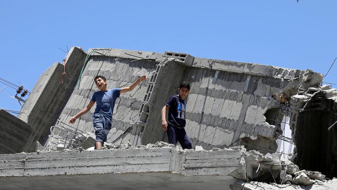 Seorang bocah Palestina menari di atas puing-puing sebuah bangunan yang baru-baru ini hancur oleh serangan udara Israel selama acara musik di kota Gaza, Selasa (14/5/2019). Acara itu menyerukan pemboikotan terhadap Kontes Lagu Eurovision 2019 yang diselenggarakan di Israel. (REUTERS/Mohammed Salem)