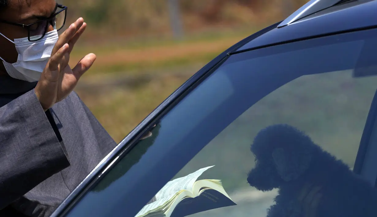 Fransiskan memberkati anjing peliharaan yang berada dalam mobil untuk mencegah penularan COVID-19 dalam misa untuk menghormati Santo Fransiskus dari Assisi pada Hari Raya Santo di Brasilia, Brasil, Senin (4/10/2021). Santo Katolik dianggap sebagai pelindung hewan. (AP Photo/Eraldo Peres)