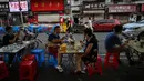 Pasangan sedang makan pada sore hari di depan sebuah restoran kecil di Wuhan, Provinsi Hubei, China, 4 Agustus 2020. Antrean panjang pelanggan sekarang terbentang di luar kios sarapan, jauh dari ketakutan akan kerumunan seperti awal pandemi COVID-19. (Hector Retamal/AFP)