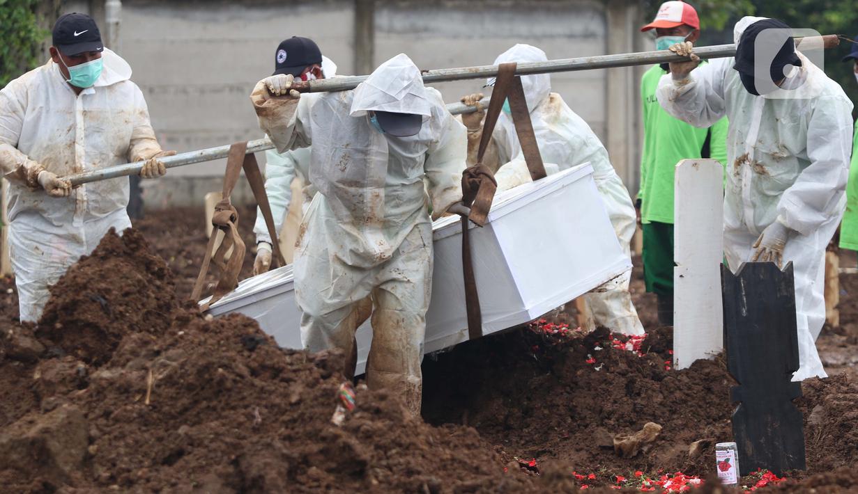 Petugas membawa peti berisi jenazah dengan protokol COVID-19 di TPU Srengseng Sawah, Jakarta, Kamis (21/1/2021). Sebagian lahan TPU Srengseng Sawah yang dijadikan lokasi pemakaman jenazah Covid-19 sejak Selasa (12/1) lalu, kini hanya tersisa 79 petak makam. (Liputan6.com/Helmi Fithriansyah)