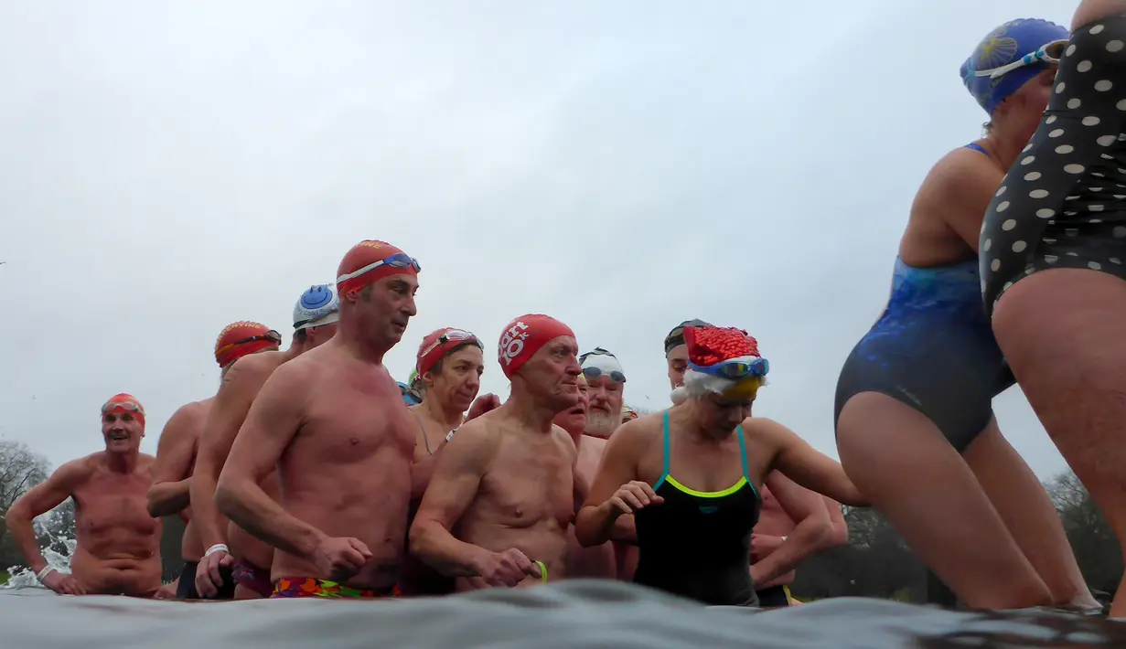 Peserta berbaris menuju tepi danau usai mengikuti lomba berenang di Danau Serpentine di Hyde Park, London, Inggris, Minggu (25/12). Lomba berenang di danau yang dingin ini sudah menjadi acara tahunan setiap perayaan natal. (REUTERS/Toby Melville)