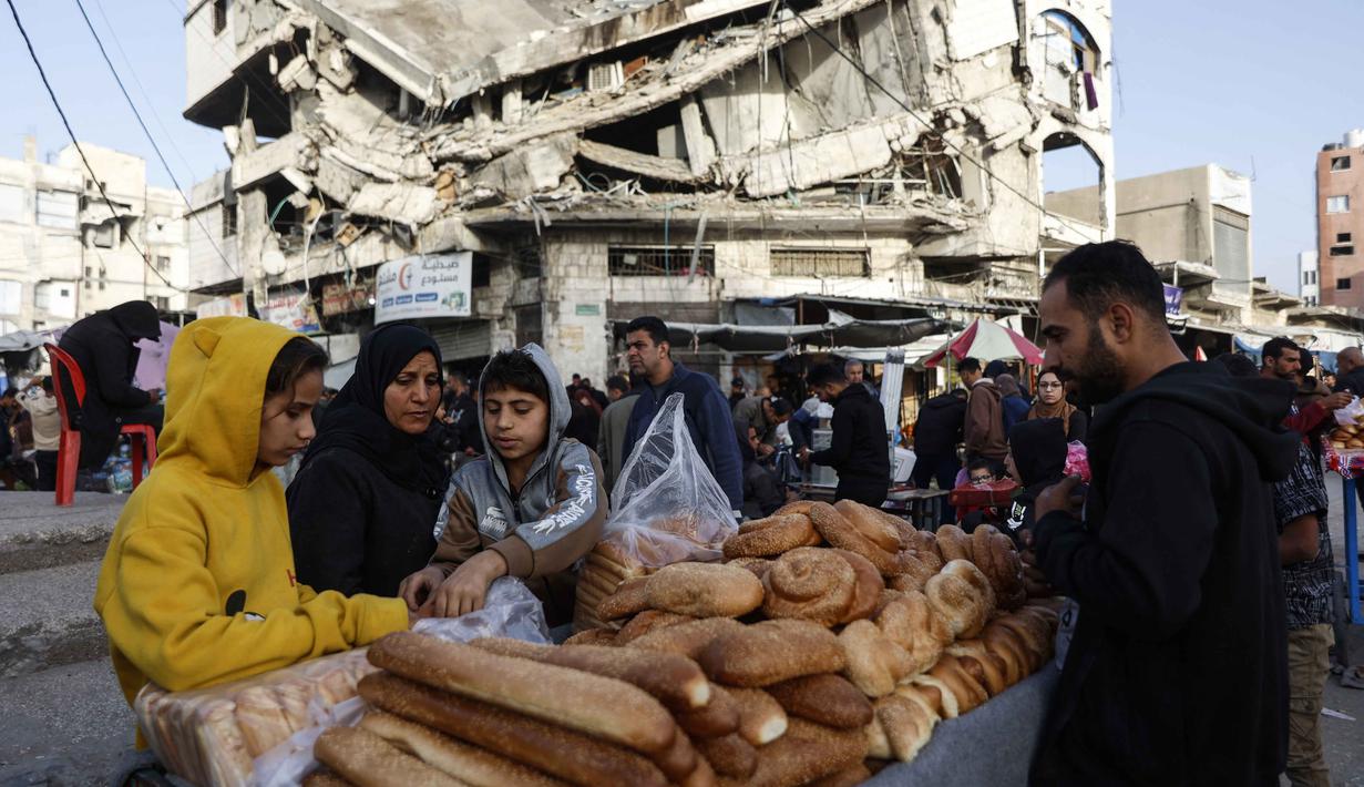 Warga Palestina menjual roti di dekat bangunan yang hancur di pasar Zawiya, Kota Gaza, pada Rabu 18 Februari 2026. Menyambut bulan suci Ramadan 1447 Hijriah, warga Palestina di Kota Gaza memadati Pasar Al-Zawiya. (Omar AL-QATTAA/AFP)