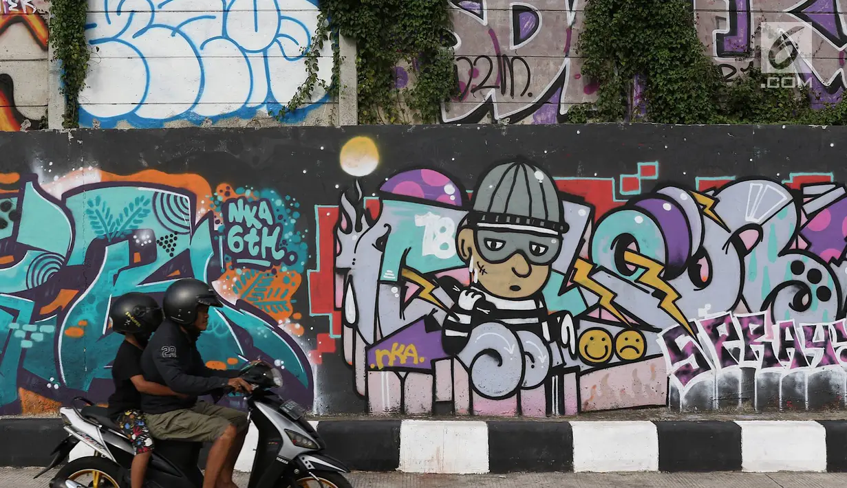 Pengendara melintasi jalur inspeksi Sungai Ciliwung di Jakarta, Kamis (27/12). Mural yang dibuat oleh beberapa komunitas tersebut menjadikan jalur inspeksi Sungai Ciliwung tampak lebih berwarna dan asri. (Liputan6.com/Immanuel Antonius)