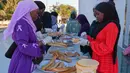 Menjelang waktu berbuka puasa, kelompok pemuda menyiapkan paket makanan ringan seperti roti isi sosis dan air. Tampak dalam foto, para wanita menyiapkan iftar, yaitu makanan berbuka puasa selama bulan suci Ramadan di Dakar, Senegal, Kamis, 5 Maret 2026. (AP Photo/Misper Apawu)