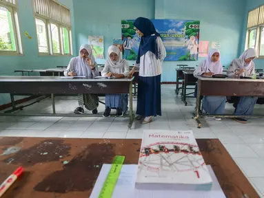 Seorang guru memberikan pelajaran matematika kepada empat murid baru kelas X di SMA 1 Muhammadiyah Depok,  Jawa Barat, Selasa (22/7/2025). (merdeka.com/Arie Basuki)