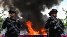 Petugas polisi militer Kamboja berjaga di depan tumpukan narkoba yang terbakar selama upacara penghancuran untuk memperingati "Hari Internasional Melawan Penyalahgunaan Narkoba dan Perdagangan Gelap" di Phnom Penh pada 28 Juni 2023.
(AFP/TANG CHHIN SOTHY)