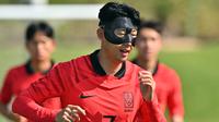 Kapten timnas Korea Selatan Son Heung-min mengenakan masker pelindung saat mengikuti sesi latihan menjelang dimulainya Piala Dunia 2022 Qatar, di Al Egla Training Site 5 di Doha, Rabu (16/11/2022). Son tampil dengan topeng, yang tampaknya terbuat dari serat karbon yang biasa digunakan dalam beberapa tahun terakhir. (Jung Yeon-je / AFP)