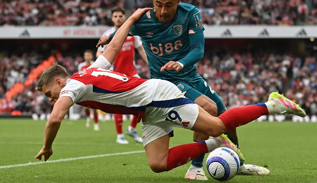 Pemain Arsenal, Leandro Trossard (kiri) terjatuh saat berebut bola dengan pemain Bournemouth, Julian Araujo dalam laga lanjutan Liga Inggris 2024/2025 di Emirates Stadium, London, Inggris, Sabtu (03/05/2025) waktu setempat. (AFP/Glyn Kirk)