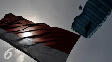 Seorang Prajurit melakukan aksi terjun Payung membawa bendera Merah Putih dalam Rangkaian Peringatan HUT TNI AU ke - 70 di Lanud Halim Perdanakusuma, Jakarta, (9/4). Sejumlah atraksi ditampilkan oleh prajurit TNI AU. (Liputan6.com/Johan Tallo)