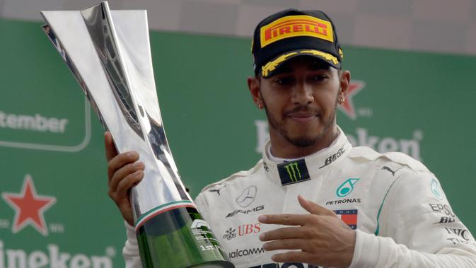 Pembalap Mercedes, Lewis Hamilton berpose dengan trofi usai meraih kemenangan GP Italia di Sirkuit Monza di Monza, (2/9). Hamilton berhasil menang di GP Italia 2018 dengan catatan waktu terbaik 1 jam 16 menit 54,484 detik. (AP Photo/Luca Bruno)