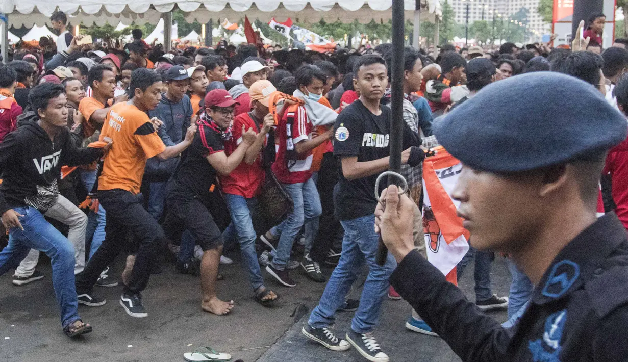 Suporter Persija Jakarta, The Jakmania, yang tidak memiliki tiket berusaha masuk area ring SUGBK dihadang pihak keamanan di Plaza Timur Senayan, Jakarta, Minggu (9/12). Persija melakoni laga penentuan juara melawan Mitra Kukar. (Bola.com/Peksi Cahyo)